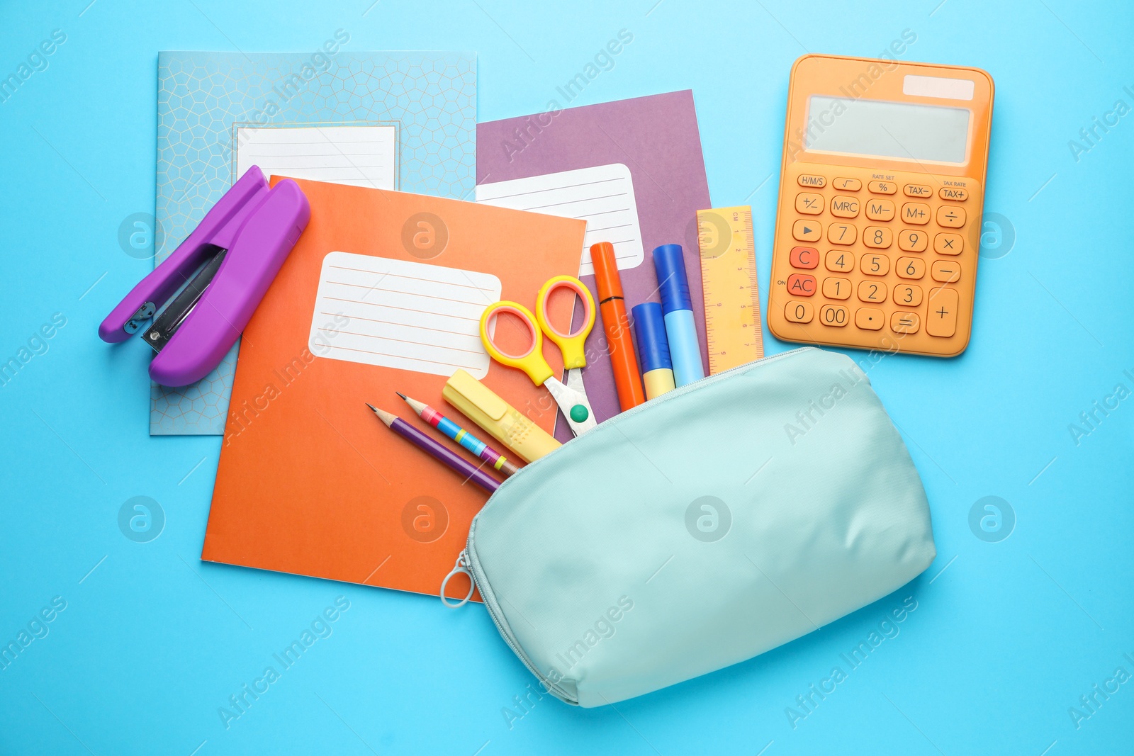 Photo of Colorful copybooks and other school stationery on light blue background, flat lay