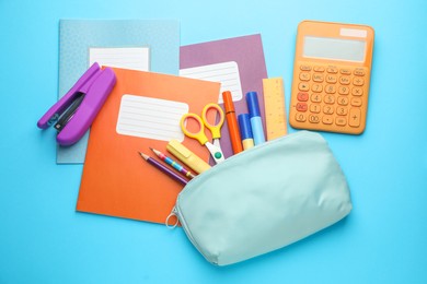 Photo of Colorful copybooks and other school stationery on light blue background, flat lay