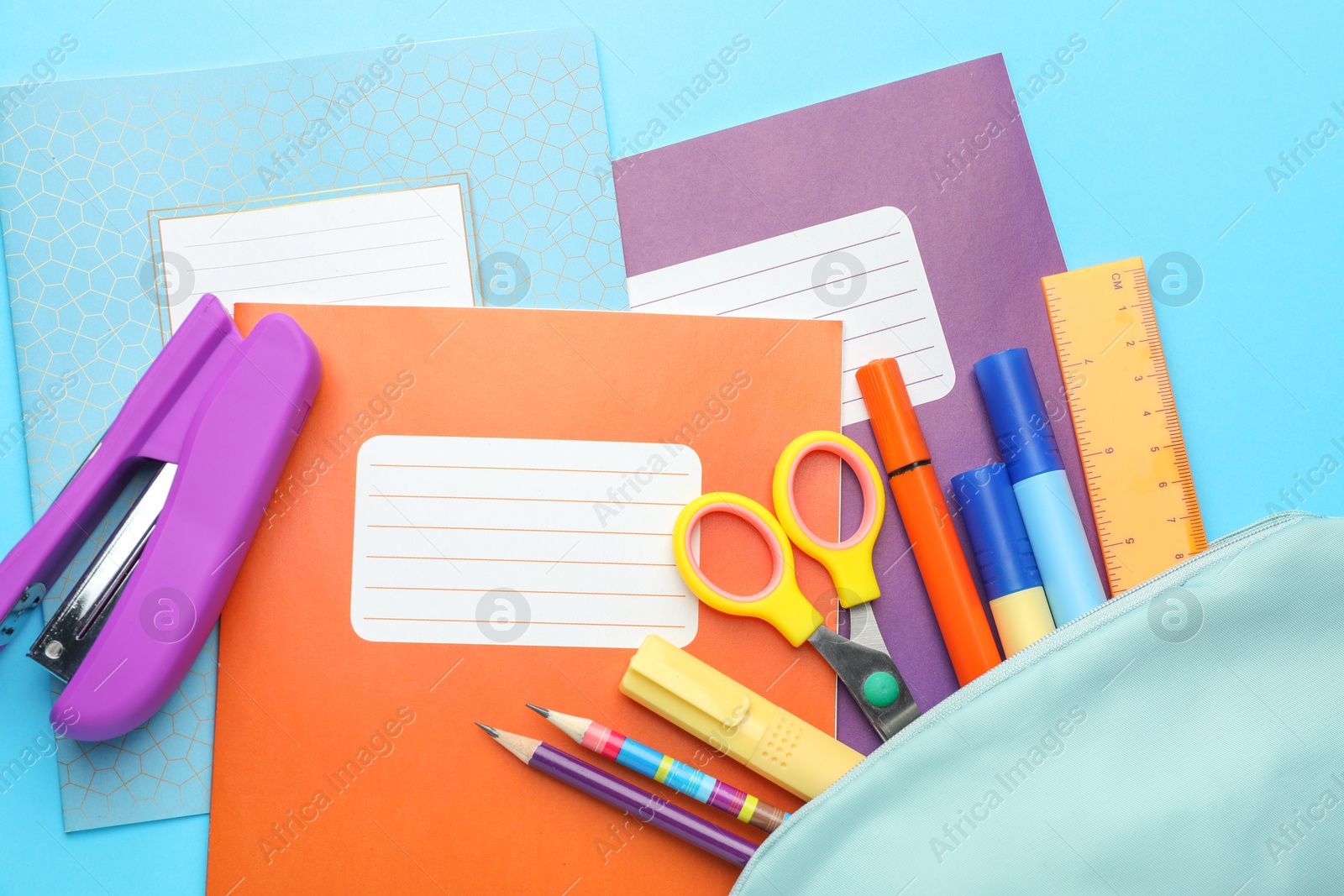 Photo of Colorful copybooks and other school stationery on light blue background, flat lay