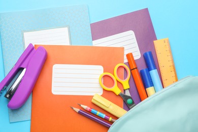 Photo of Colorful copybooks and other school stationery on light blue background, flat lay