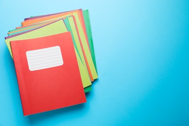 Photo of Stack of colorful copybooks on light blue background, top view. Space for text