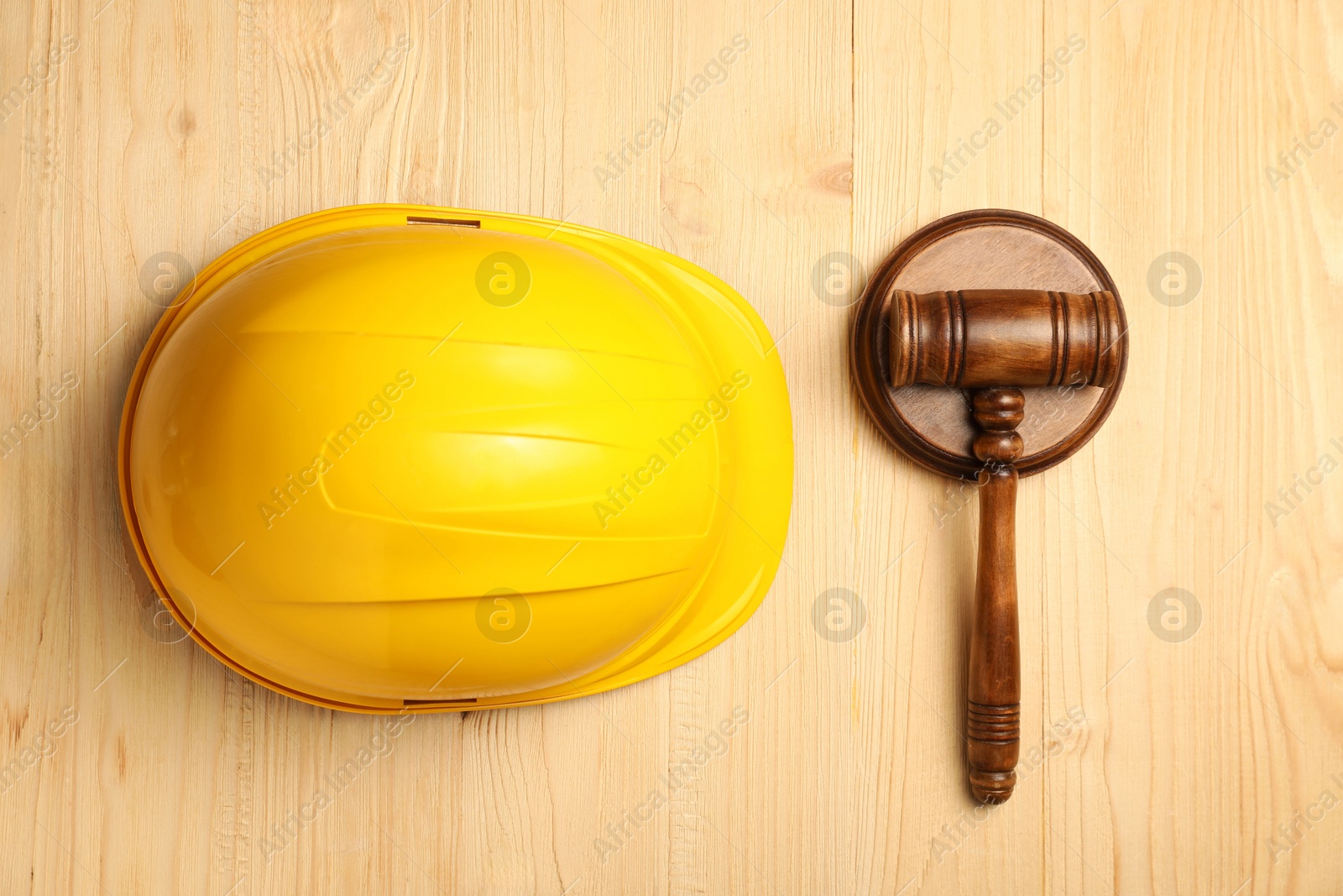 Photo of Accident at work concept. Gavel and hardhat on wooden table, top view