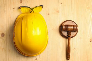 Photo of Accident at work concept. Gavel, hardhat and protective goggles on wooden table, flat lay