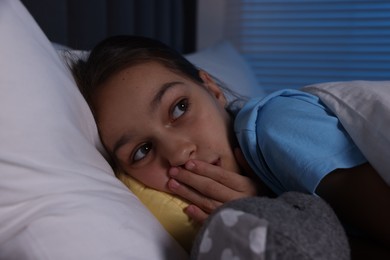 Photo of Afraid girl with toy in bed at night