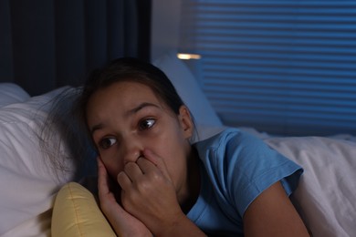 Fearful girl lying on bed at night