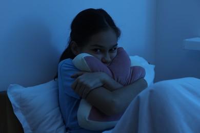 Photo of Afraid girl with pillow in bed at night