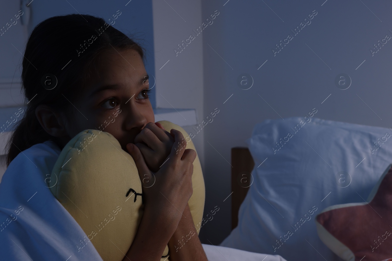 Photo of Afraid girl with pillow in bed at night. Space for text