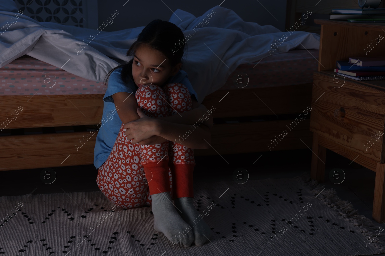 Photo of Afraid girl near bed in her room at night. Space for text