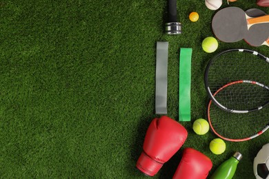 Photo of Different sport equipment on artificial grass, flat lay. Space for text