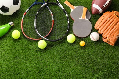 Photo of Different sport equipment on artificial grass, flat lay. Space for text