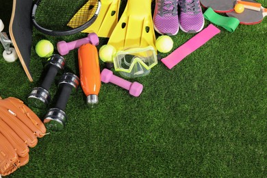 Photo of Different sport equipment on artificial grass, above view. Space for text