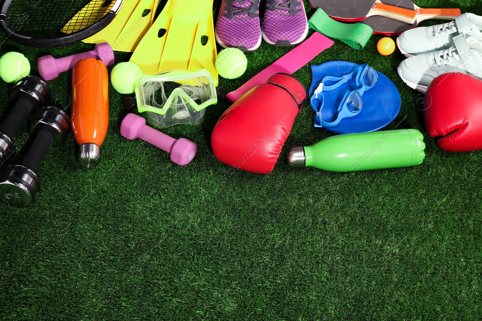 Photo of Different sport equipment on artificial grass, above view. Space for text