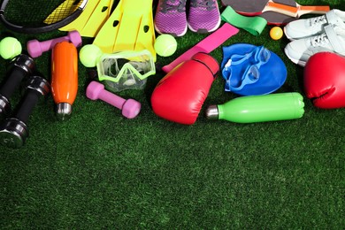 Photo of Different sport equipment on artificial grass, above view. Space for text