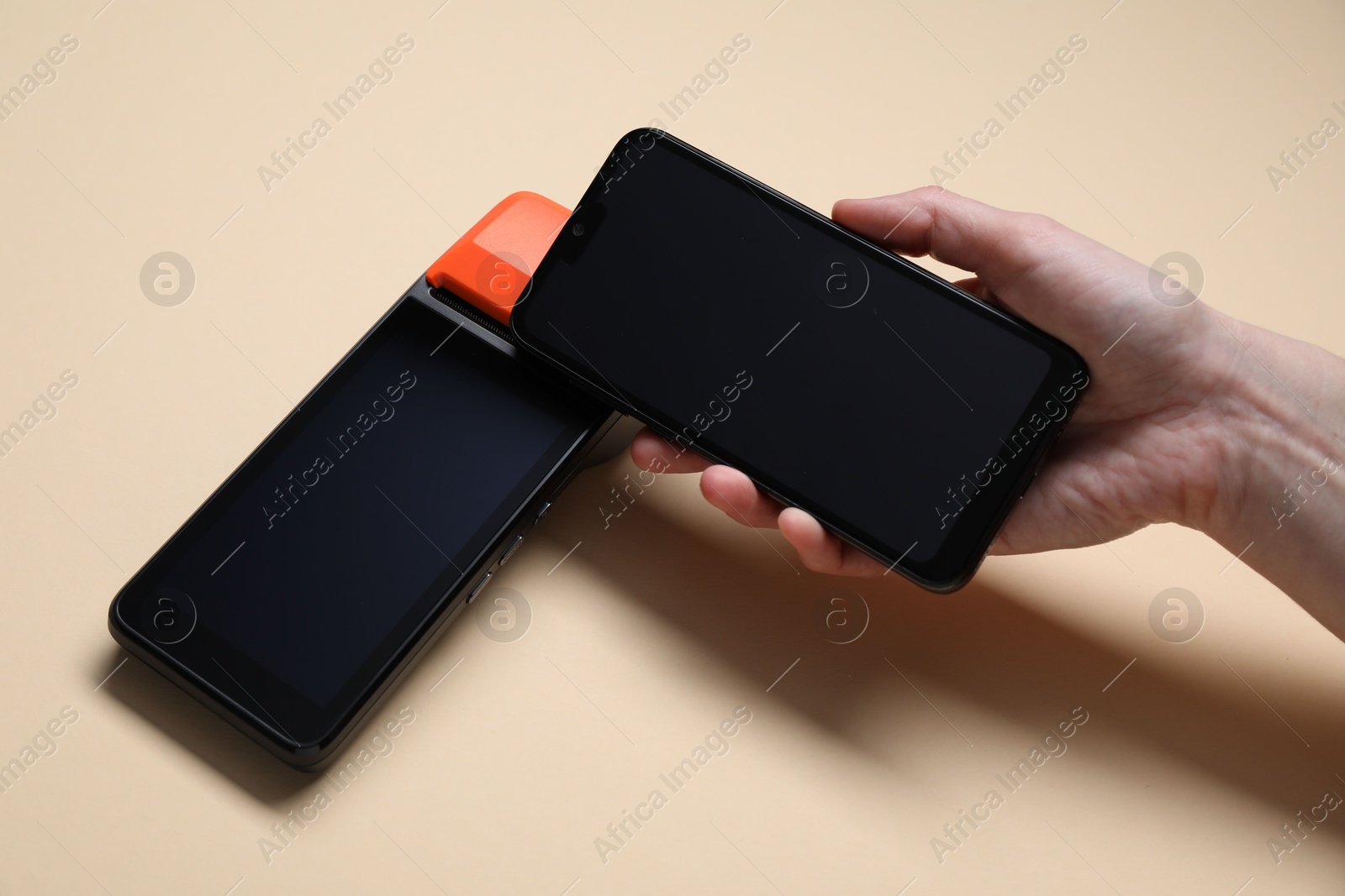 Photo of Woman with smartphone using payment terminal on beige background, closeup