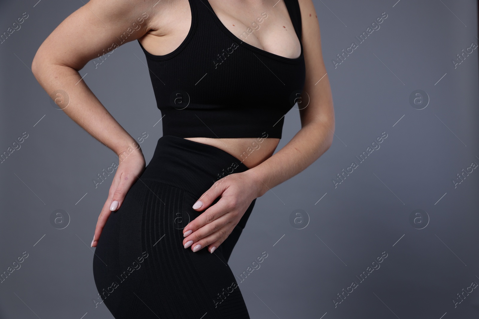 Photo of Woman in sportswear on grey background, closeup. Space for text