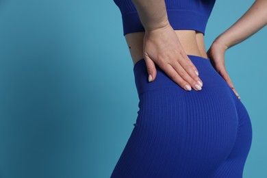 Woman in sportswear on light blue background, closeup. Space for text