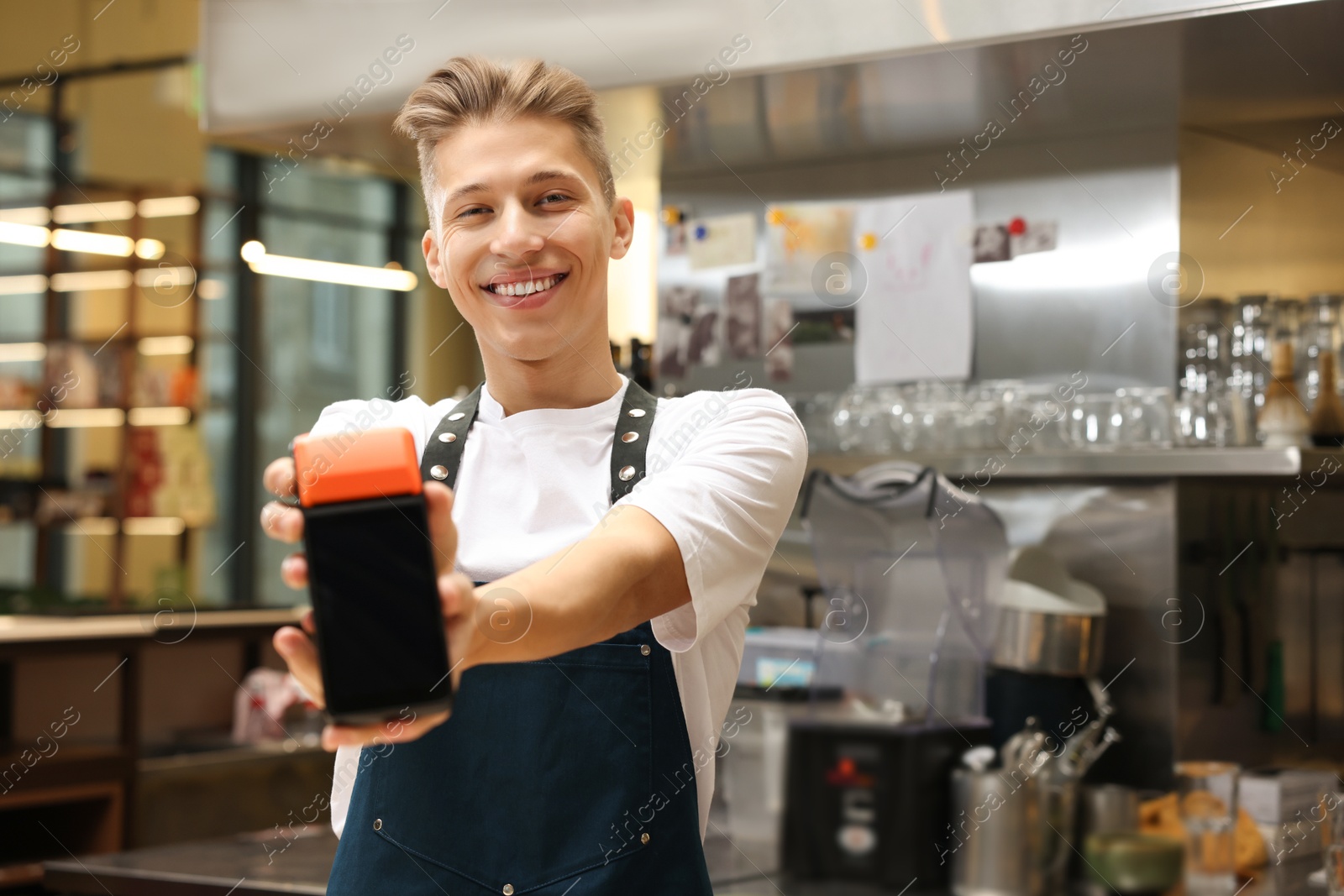 Photo of Smiling cafe worker with payment terminal indoors