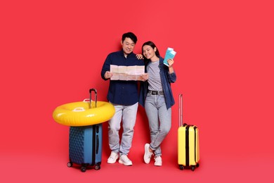 Photo of Travellers with passports, map, inflatable ring and suitcases on red background