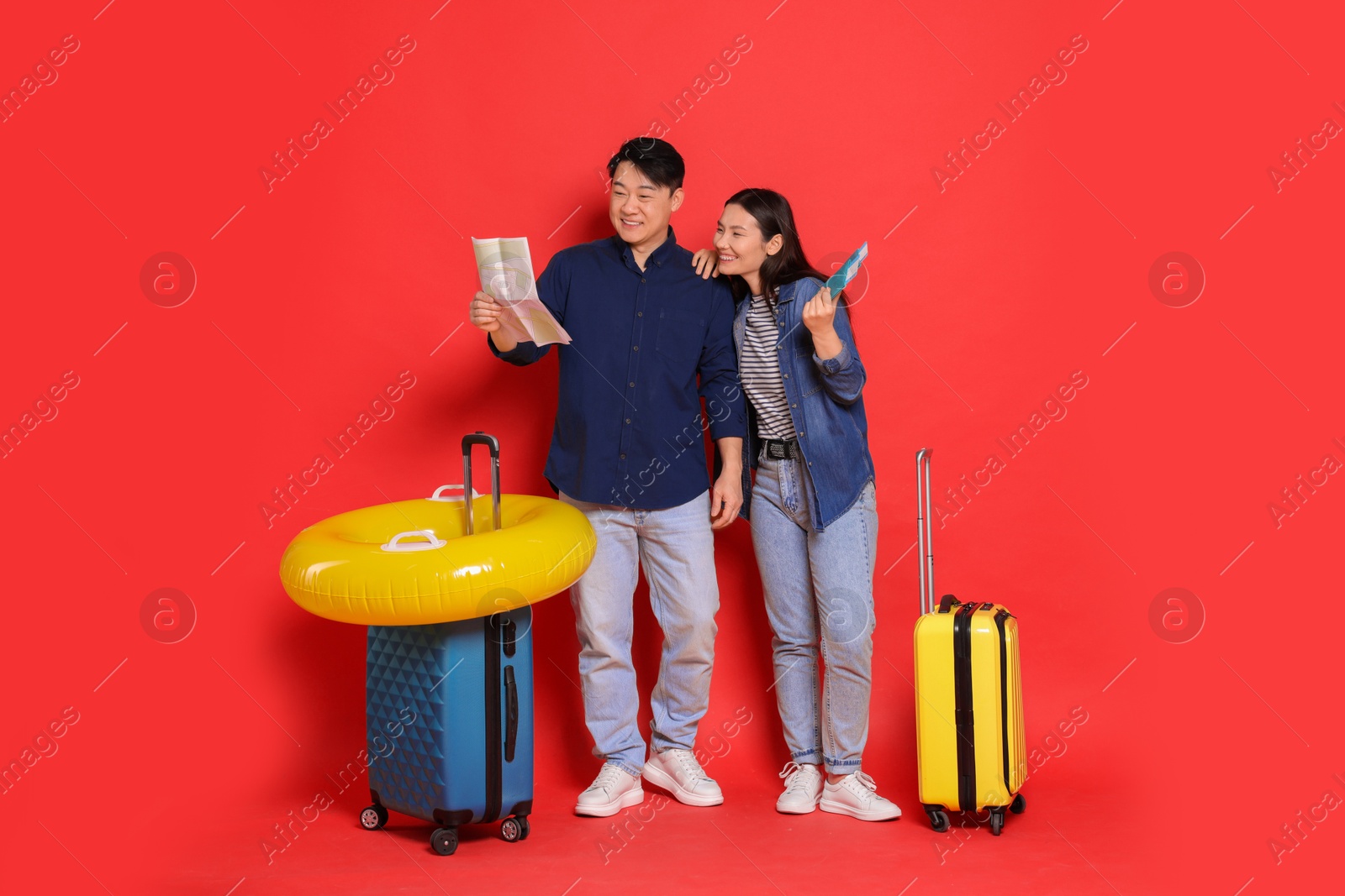 Photo of Travellers with passports, map, inflatable ring and suitcases on red background