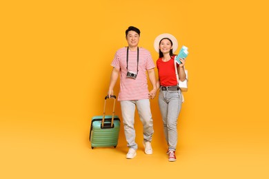 Photo of Happy travellers with passports and suitcase on yellow background