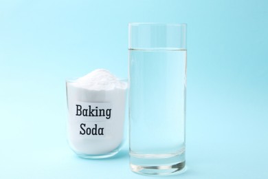 Photo of Glass of water and baking soda on light blue background