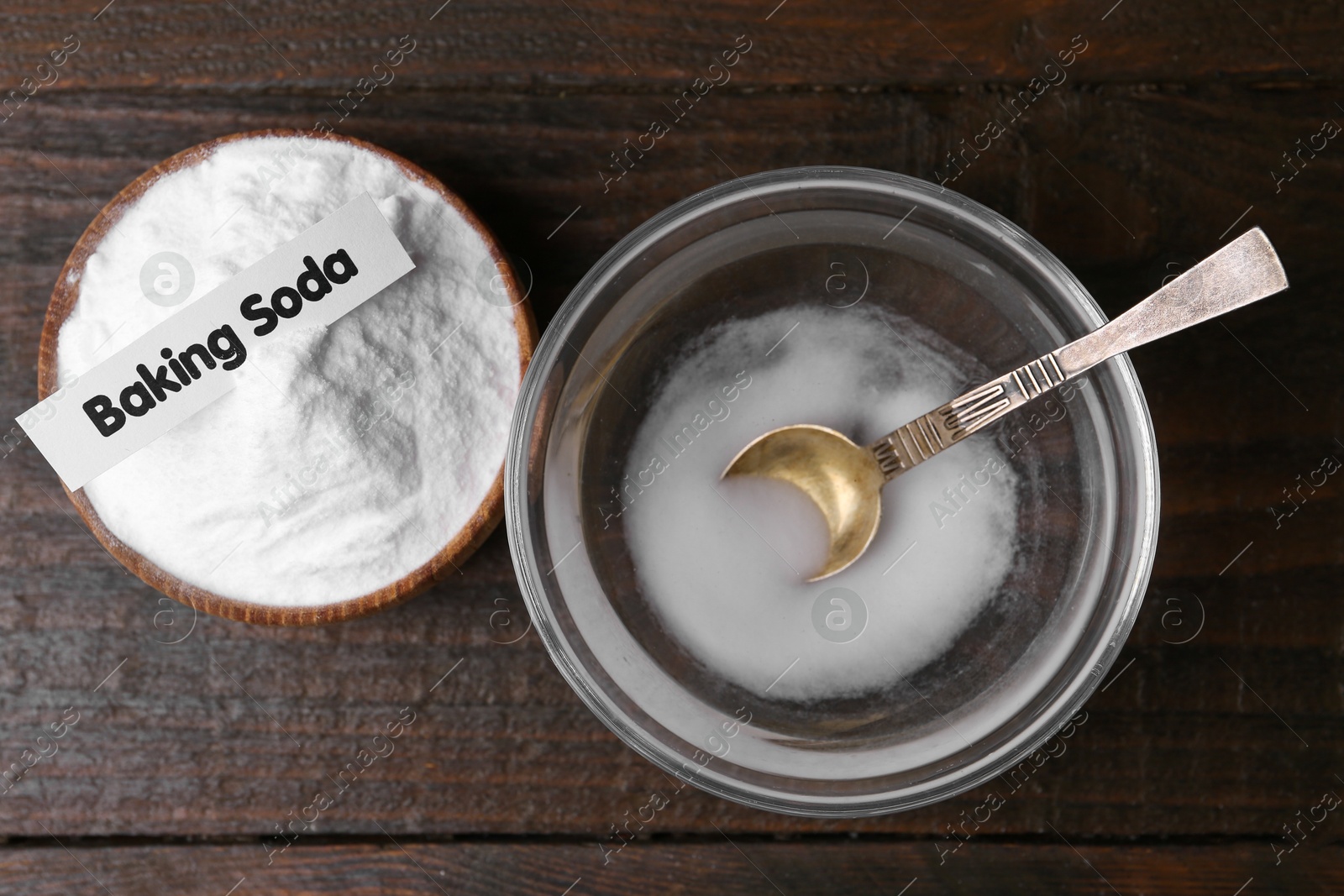 Photo of Bowl with water and baking soda on wooden table, top view