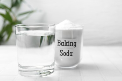 Photo of Glass of water and baking soda on white tiled table