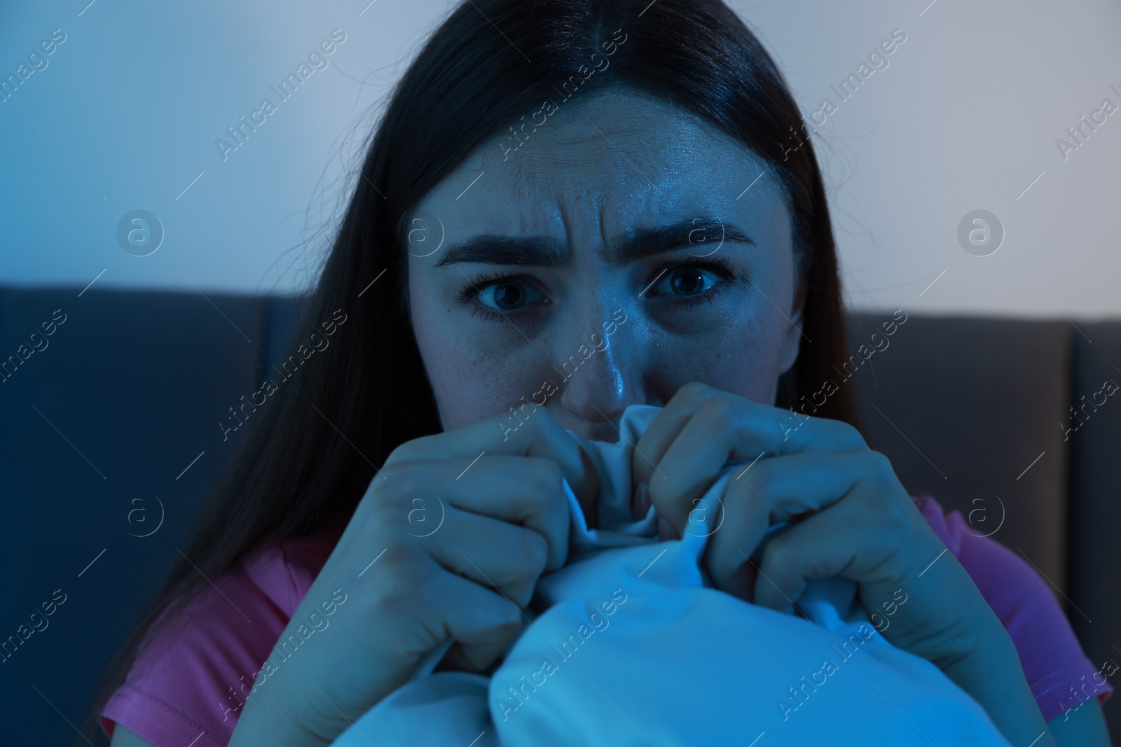 Photo of Fear of darkness. Scared young woman on bed in room at night