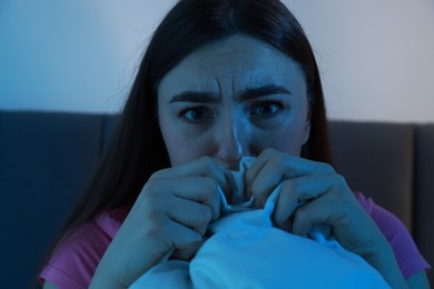 Fear of darkness. Scared young woman on bed in room at night