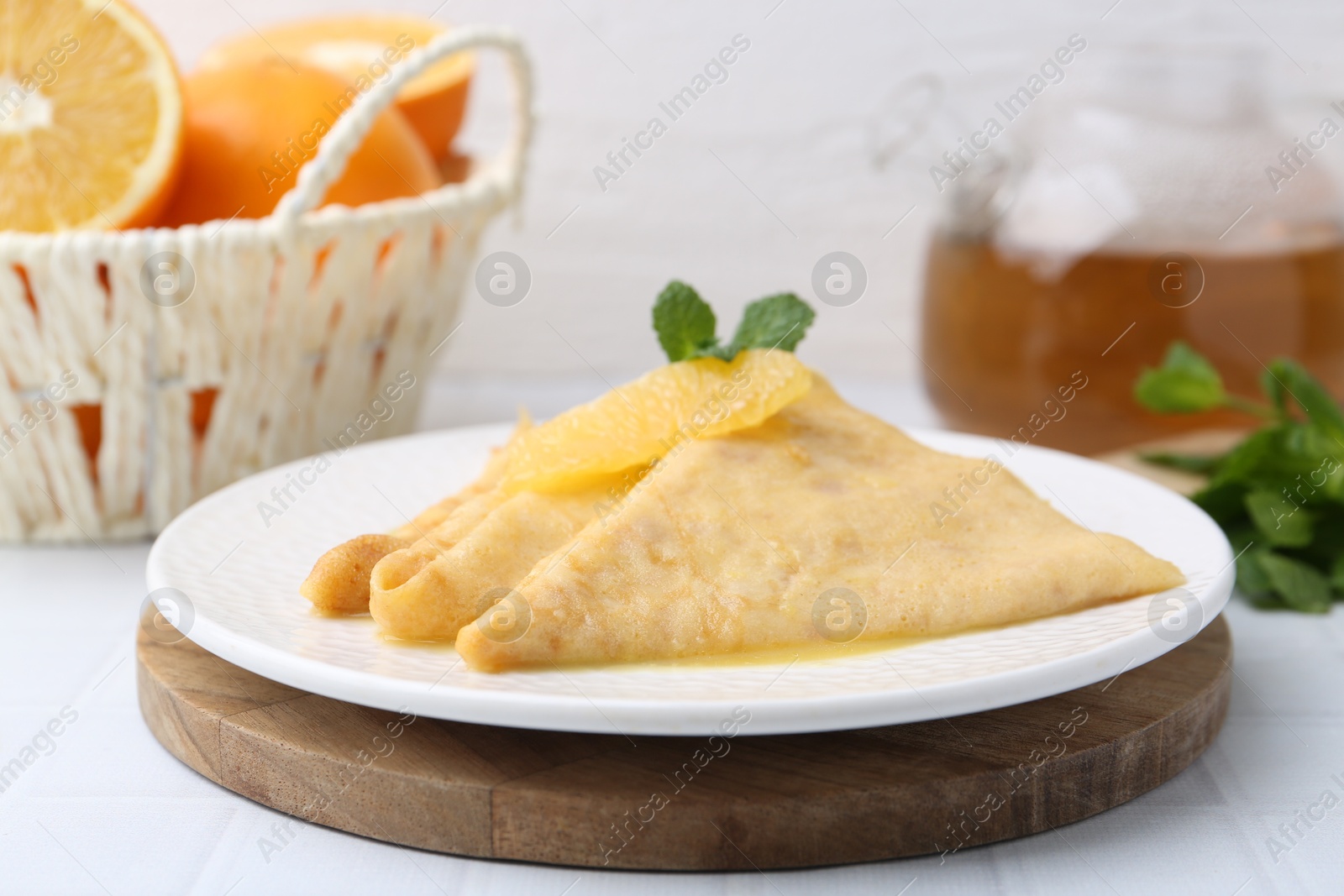 Photo of Tasty crepes Suzette on white tiled table, closeup