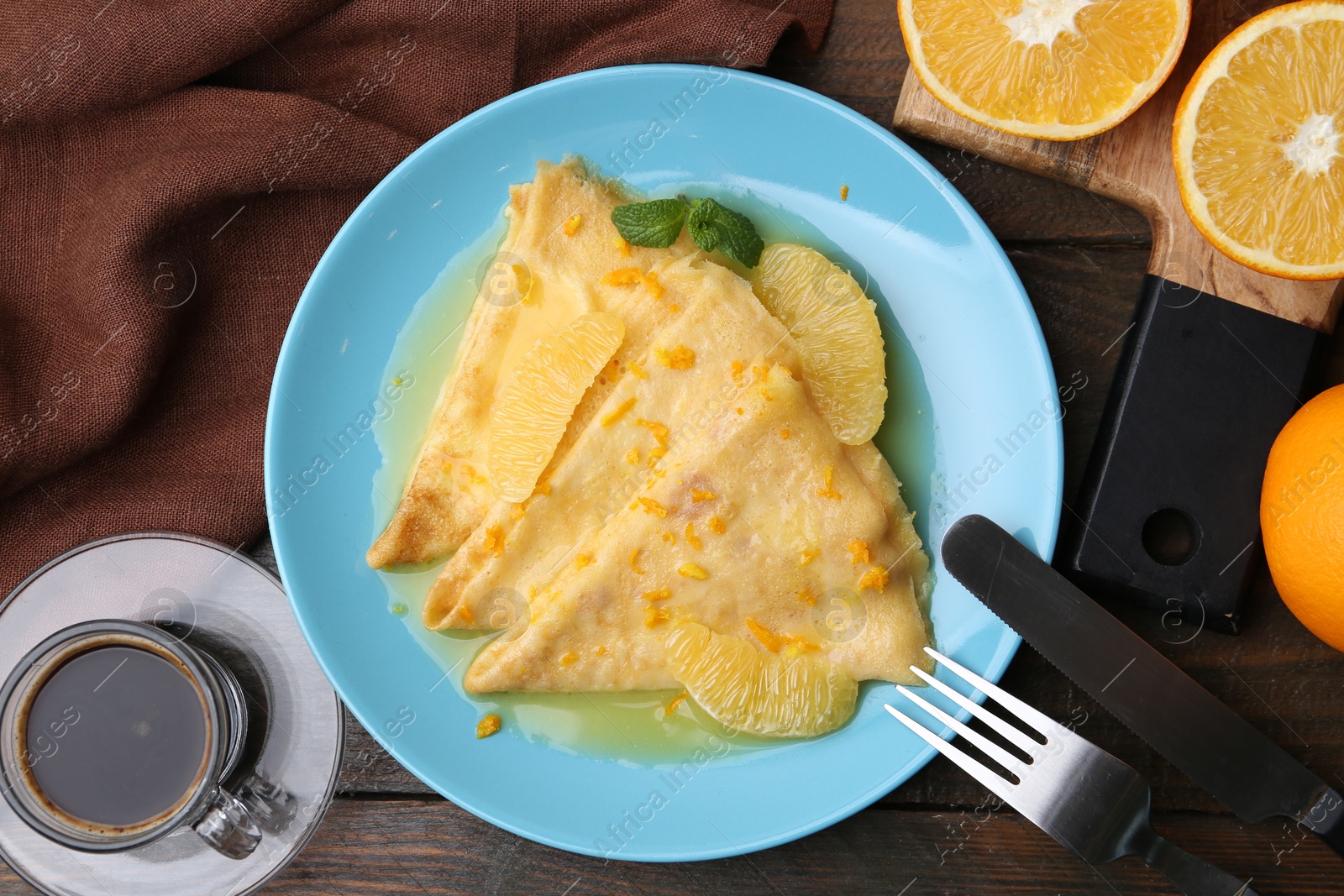 Photo of Plate with tasty crepes Suzette served on wooden table, flat lay