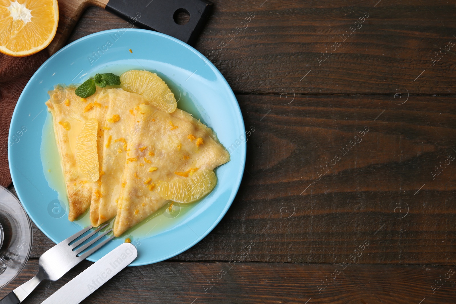 Photo of Plate with tasty crepes Suzette served on wooden table, flat lay. Space for text