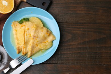 Photo of Plate with tasty crepes Suzette served on wooden table, flat lay. Space for text