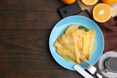 Photo of Tasty crepes Suzette served on wooden table, flat lay. Space for text