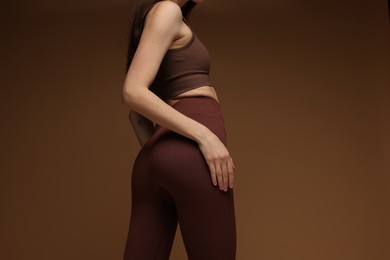 Woman in stylish sportswear on brown background, closeup