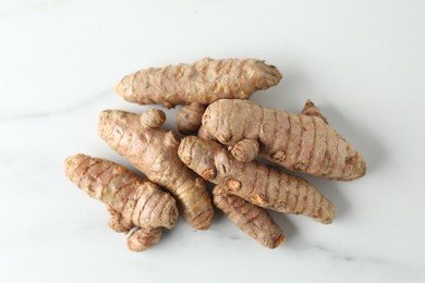 Photo of Raw turmeric roots on white marble table, top view