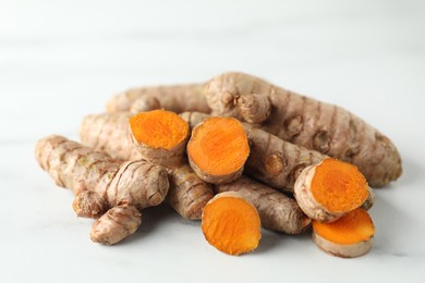 Photo of Pile of raw turmeric roots on white table, closeup