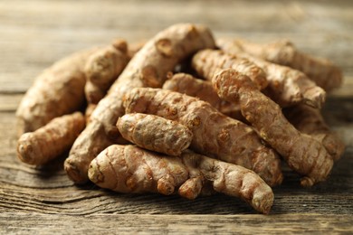 Photo of Pile of tumeric rhizomes on wooden table, closeup