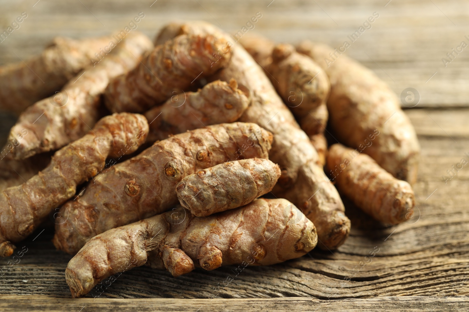 Photo of Pile of tumeric rhizomes on wooden table, closeup