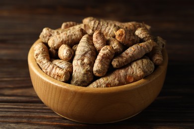 Photo of Tumeric rhizomes in bowl on wooden table, closeup