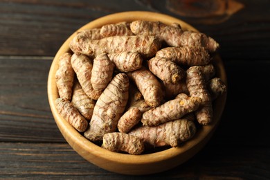 Photo of Tumeric rhizomes in bowl on wooden table, closeup