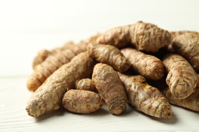 Photo of Pile of tumeric rhizomes on white wooden table, closeup