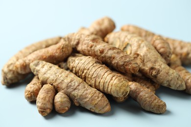 Photo of Pile of tumeric rhizomes on light blue background, closeup