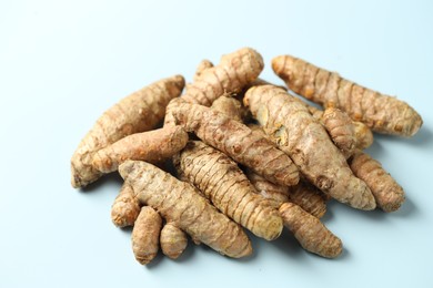 Photo of Pile of tumeric rhizomes on light blue background, closeup