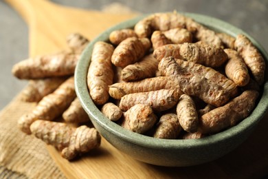 Photo of Tumeric rhizomes in bowl on grey table, closeup