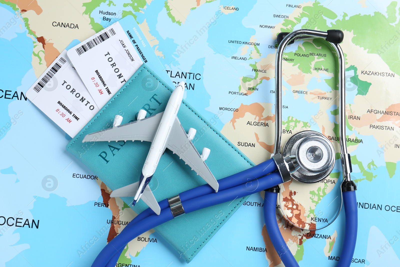 Photo of Medical tourism. Passport with tickets, stethoscope and airplane model on world map, top view