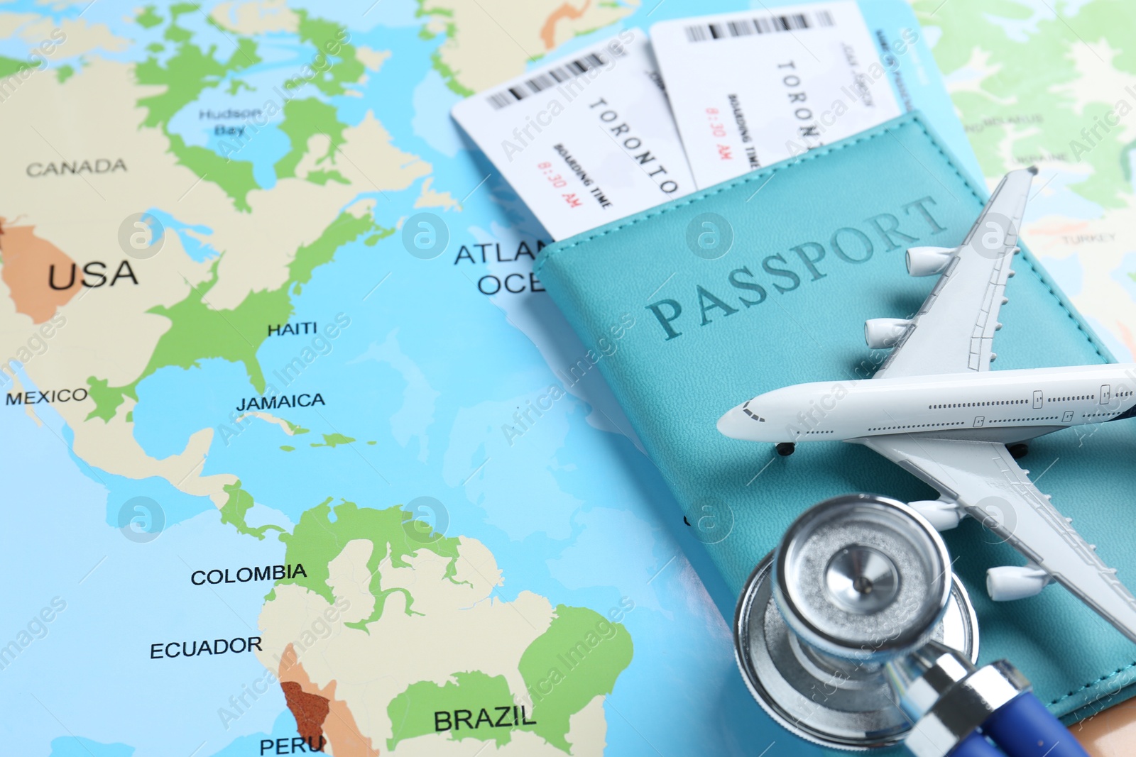 Photo of Medical tourism. Passport with tickets, stethoscope and airplane model on world map, closeup