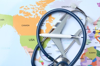 Photo of Medical tourism. Stethoscope and airplane model on world map, top view