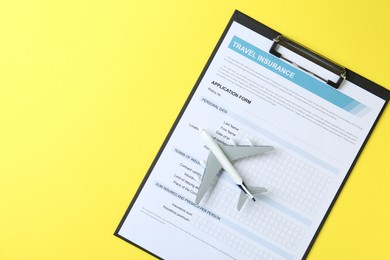 Photo of Medical tourism. Travel insurance application form and airplane model on yellow background, top view. Space for text