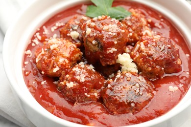 Photo of Delicious meatballs with tomato sauce, parmesan cheese and parsley in bowl, closeup